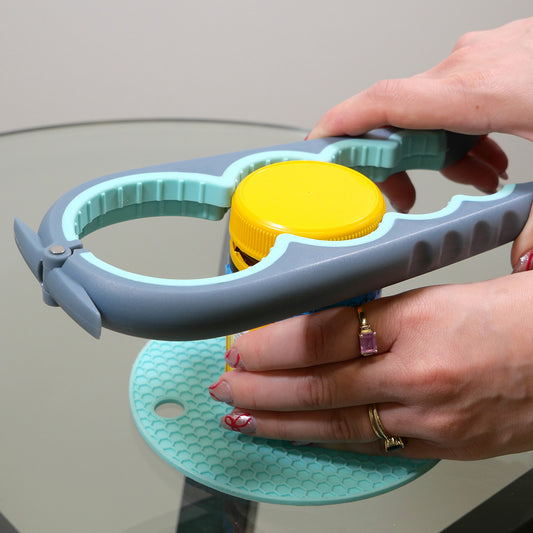 Person using a Goldfern GripMate Jar and Bottle Opener with a yellow cap on a light gray background