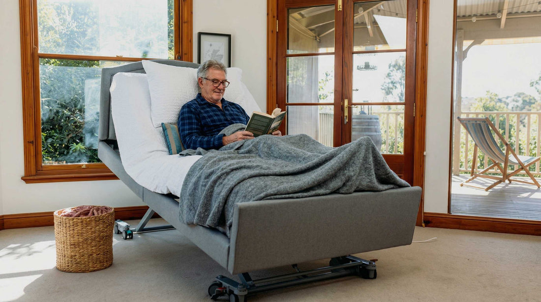 Man in a healthcare bed reading in a bedroom setting