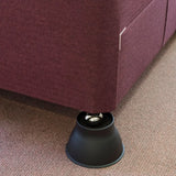A close-up of a Derby Elephant Feet Furniture Raiser 9cm resting on a black circular floor pad over a textured carpet.