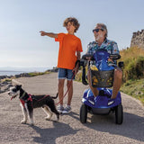 Man on a Invacare Leo Mobility Scooter  with a young boy and a dog by the seaside.