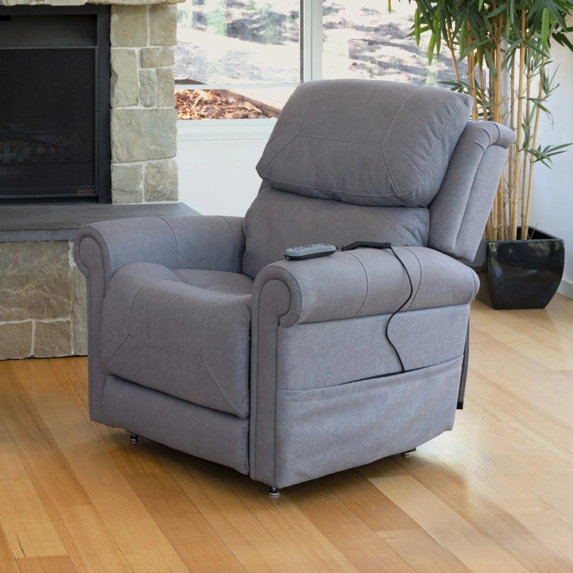 Theorem Studio Power Lift Recliner Chair in a living room setting with a fireplace and potted plant.