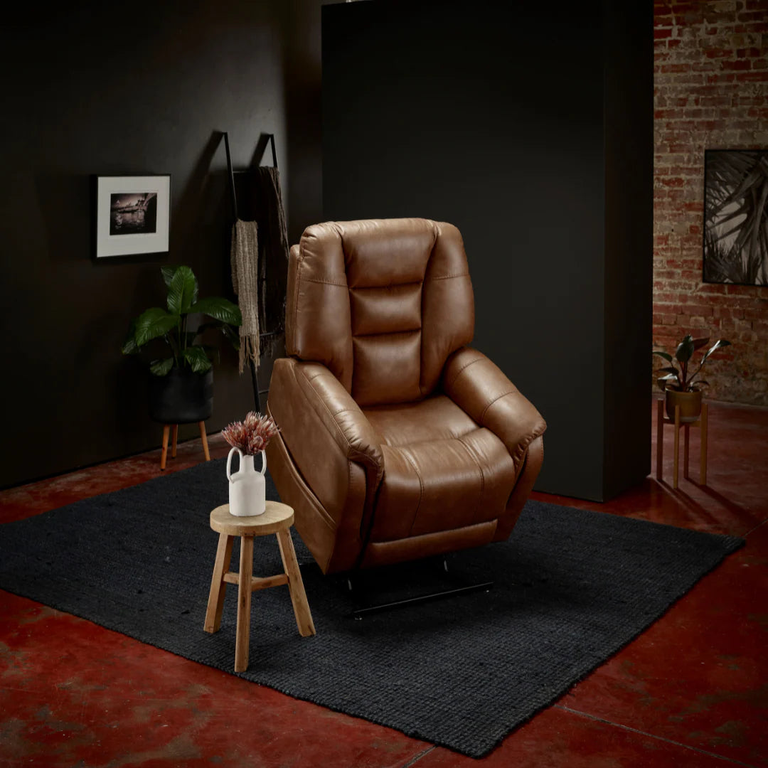 Theorem Mercer Power Lift Recliner Chair Saddle in a dimly lit room with a dark wall and brick wall.