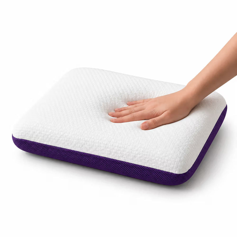 A white icare Classic Pillow with a purple fabric border, shown on a white background with a hand pressing down on the center to demonstrate its contouring.
