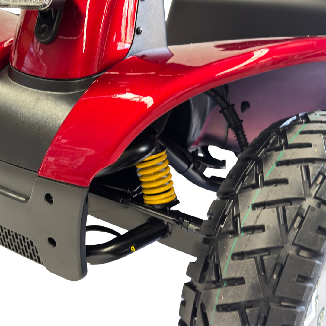 Close-up of a Pride Mobility Pathrider 130 XL Mobility Scooter's suspension system with a yellow shock absorber on a white background.
