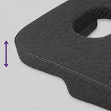 A charcoal icare Supporta Rotator Cuff Recovery Pillow with a textured surface and a central cutout, shown on a light gray background with a purple double-arrow graphic indicating height adjustability.