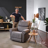 Man standing next to a Theorem Studio Power Lift Recliner Chair in Fog in a modern living room.