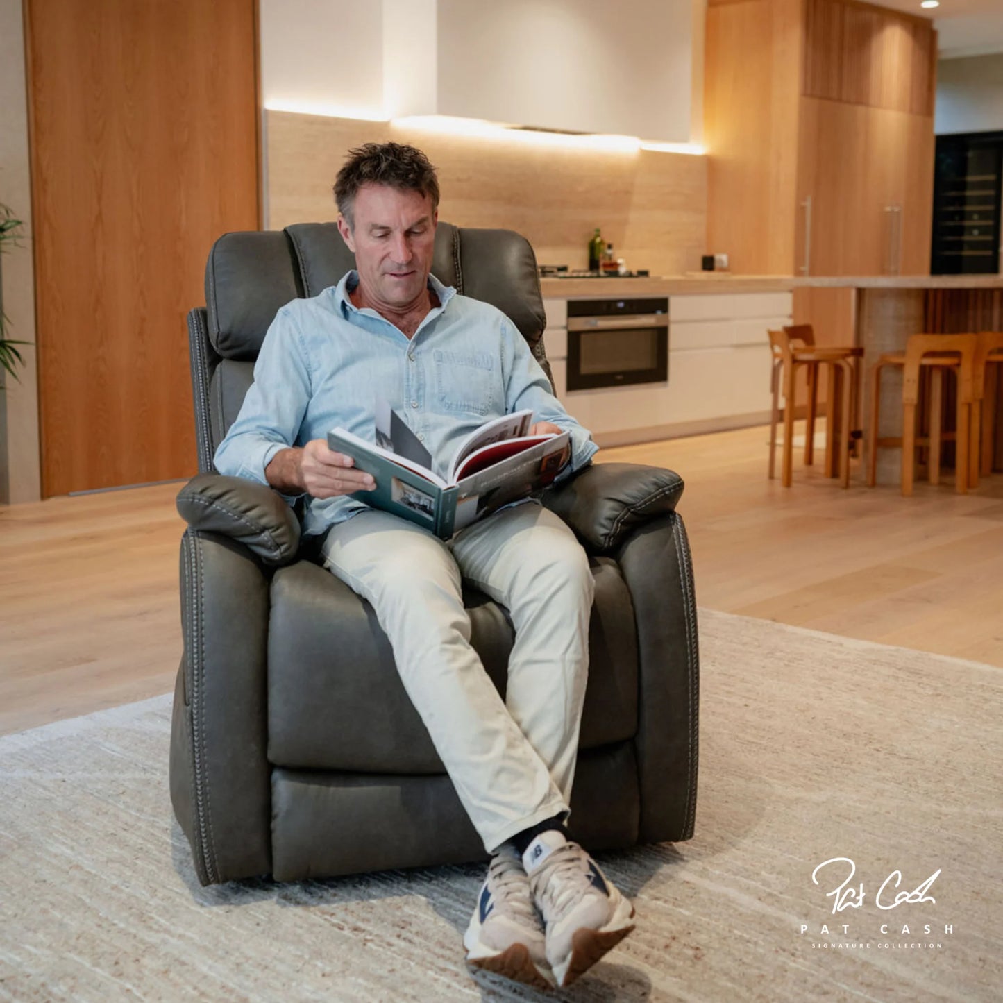 Man reading a book in a modern living room on a Theorem Winslow Power Lift Recliner Chair