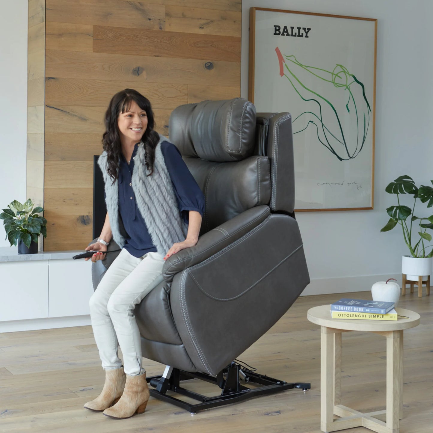 Woman sitting in a Theorem Winslow Power Lift Recliner Chair in a modern living room.