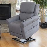 A Theorem Studio Power Lift Recliner Chair in Smoke in a lift position in a living room setting with a fireplace and plant.