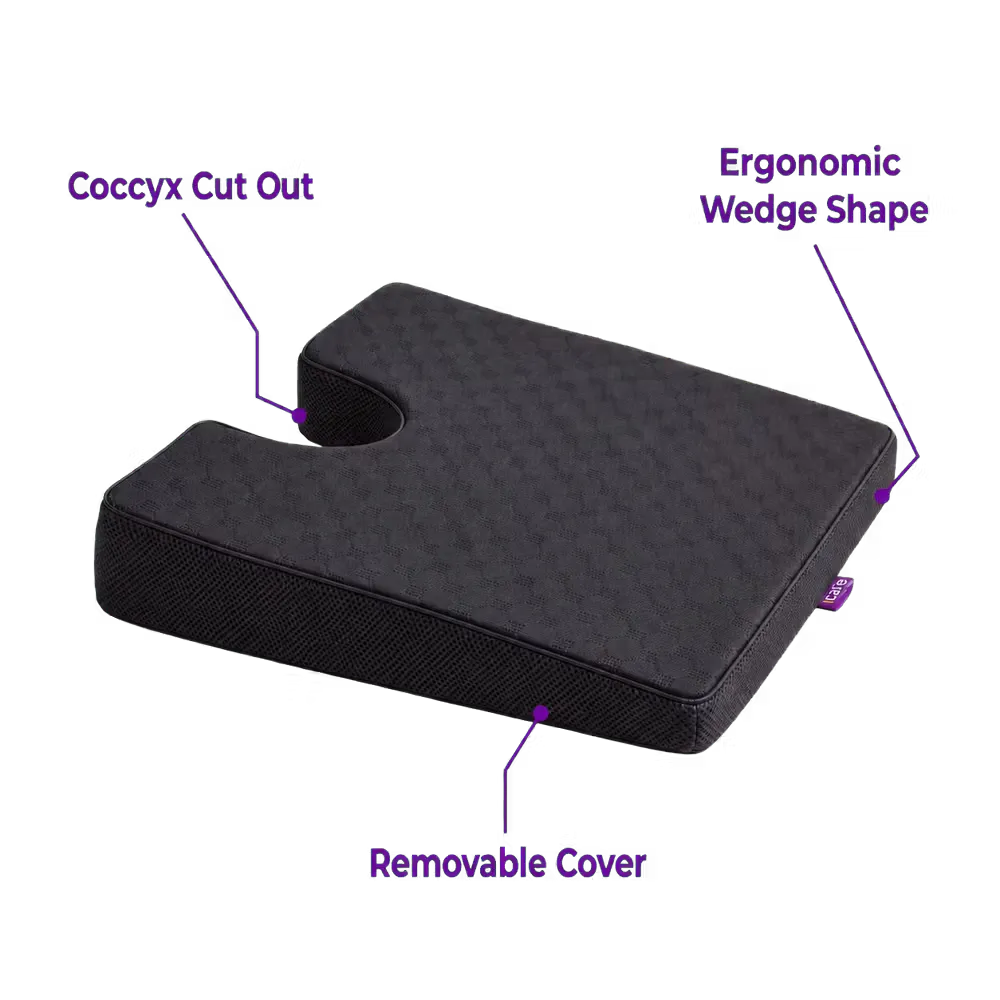 A charcoal icare Coccyx Wedge with a textured top surface, shown on a white background with purple text callouts highlighting features like the 'Coccyx Cut Out,' 'Ergonomic Wedge Shape,' and 'Removable Cover.'.