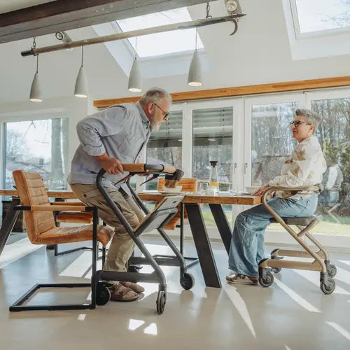 Two people using Saljol Indoor Walker at a dining table in a modern home setting.