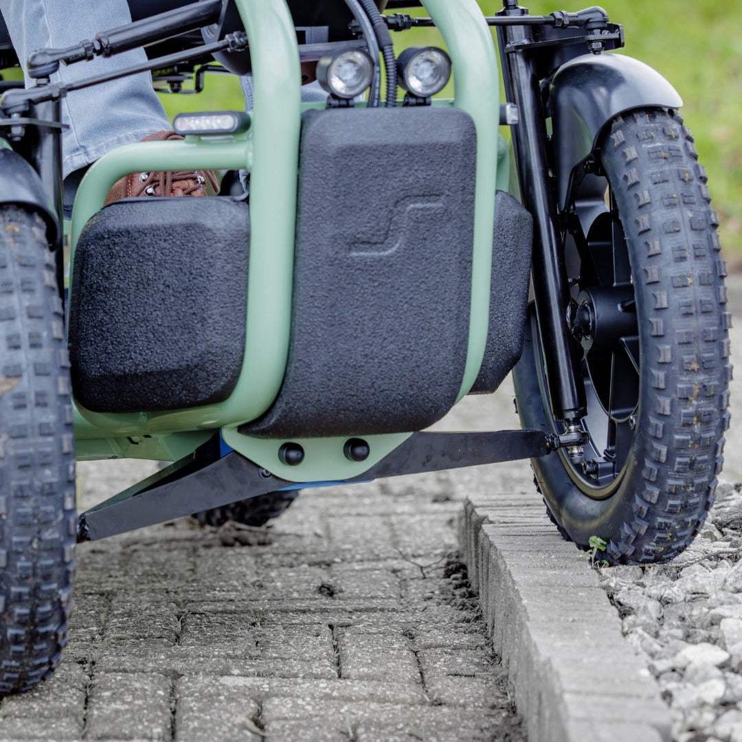 Close-up of a Sterling S800 Scooty electric three-wheeler vehicle with a mint green frame and black body panels, parked on a paved outdoor path. The Sterling brand logo is visible on the handlebar and in the top right corner.