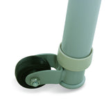 Close-up of a caster wheel attachment on a light sage green metal frame, featuring a black rubber wheel and a light green plastic swivel bracket.
