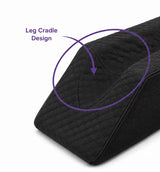 Close-up of a charcoal icare Leg Raiser cushion with a purple arrow and text reading 'Leg Cradle Design' highlighting the padded leg support area, on a white background.