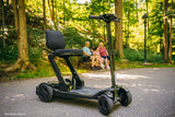 Pride GoGo Carbon Folding Travel Scooter Black in park setting