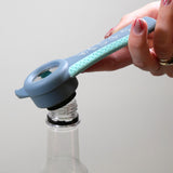 Hand using a Goldfern GripMate Jar and Bottle Opener on a clear bottle against a light gray background