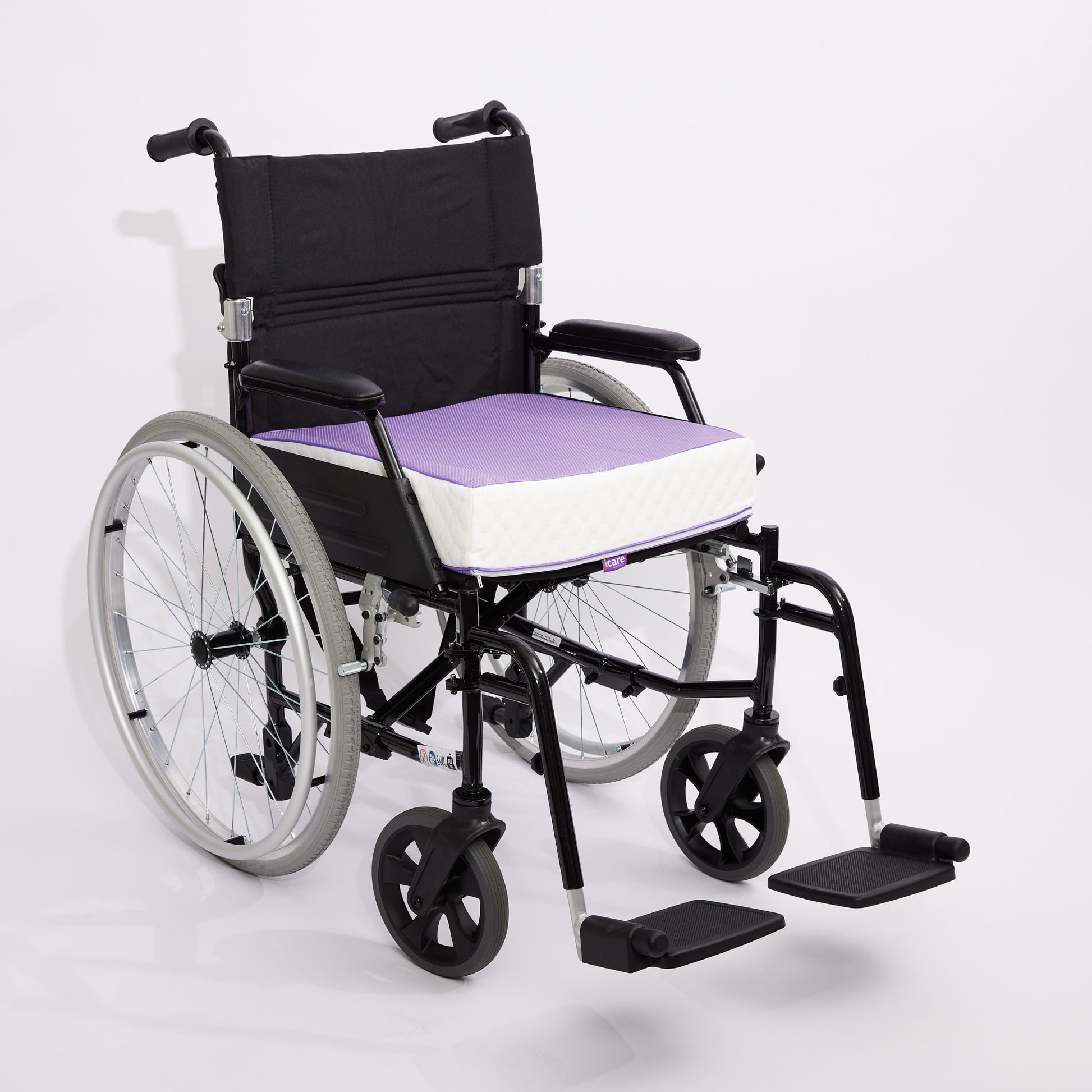 A manual wheelchair with a black frame and backrest, featuring a purple 10cm icare Supporta Seat Cushion, shown on a light gray studio background.