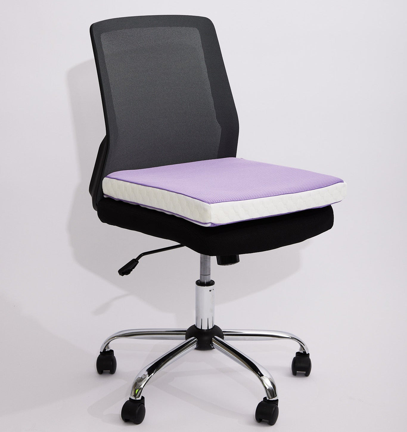 A modern office chair with a black mesh back, black fabric seat, and a light purple icare Supporta Seat Cushion on the seat, supported by a chrome five-star base with black casters.