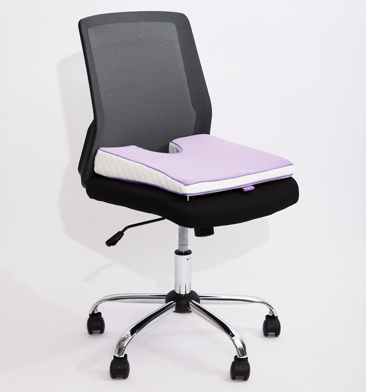 A black mesh office chair purple icare Coccyx Wedge on the seat, set against a plain white studio background.