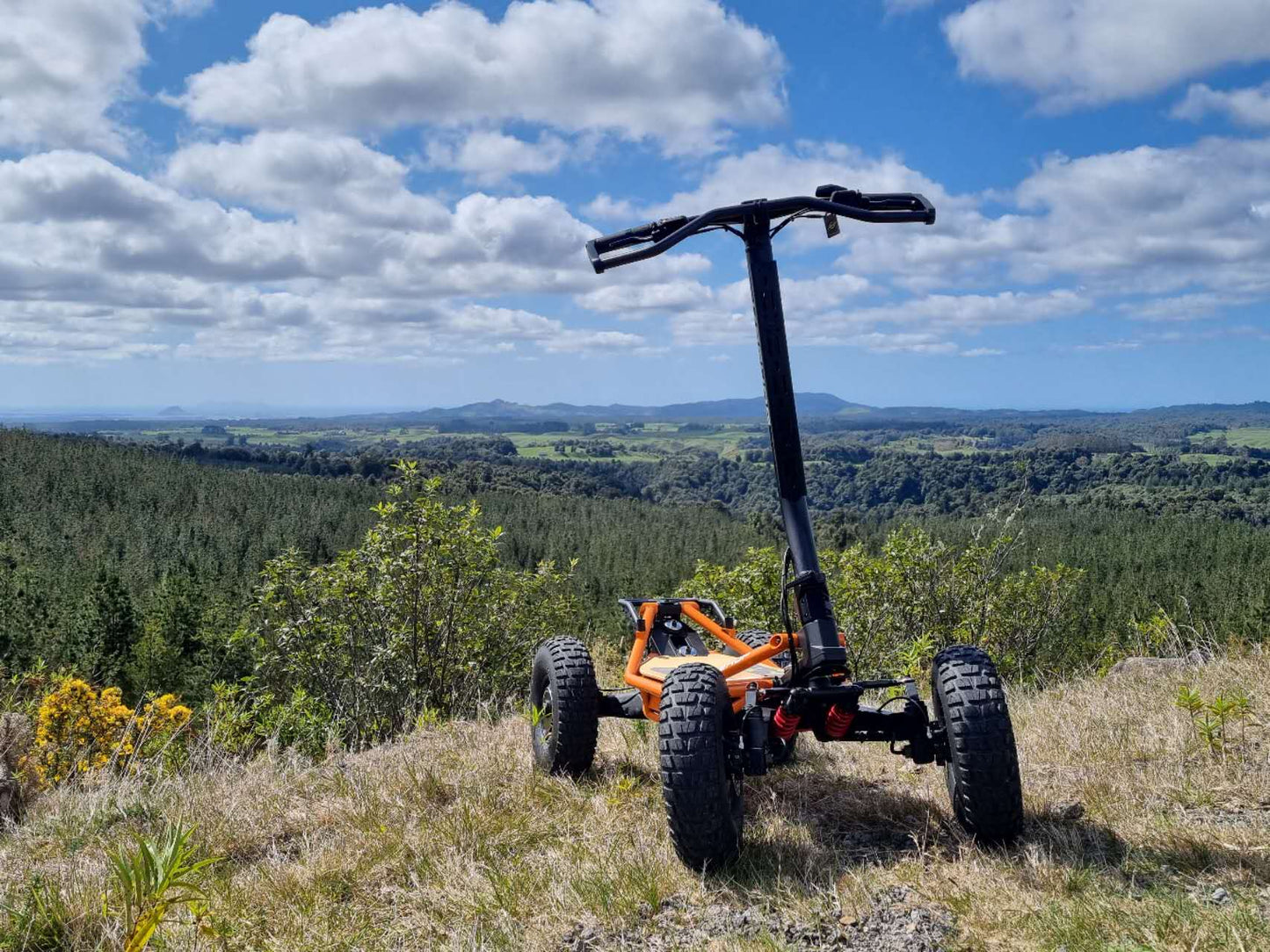 Veehop Electric ATV orange in grass on hill