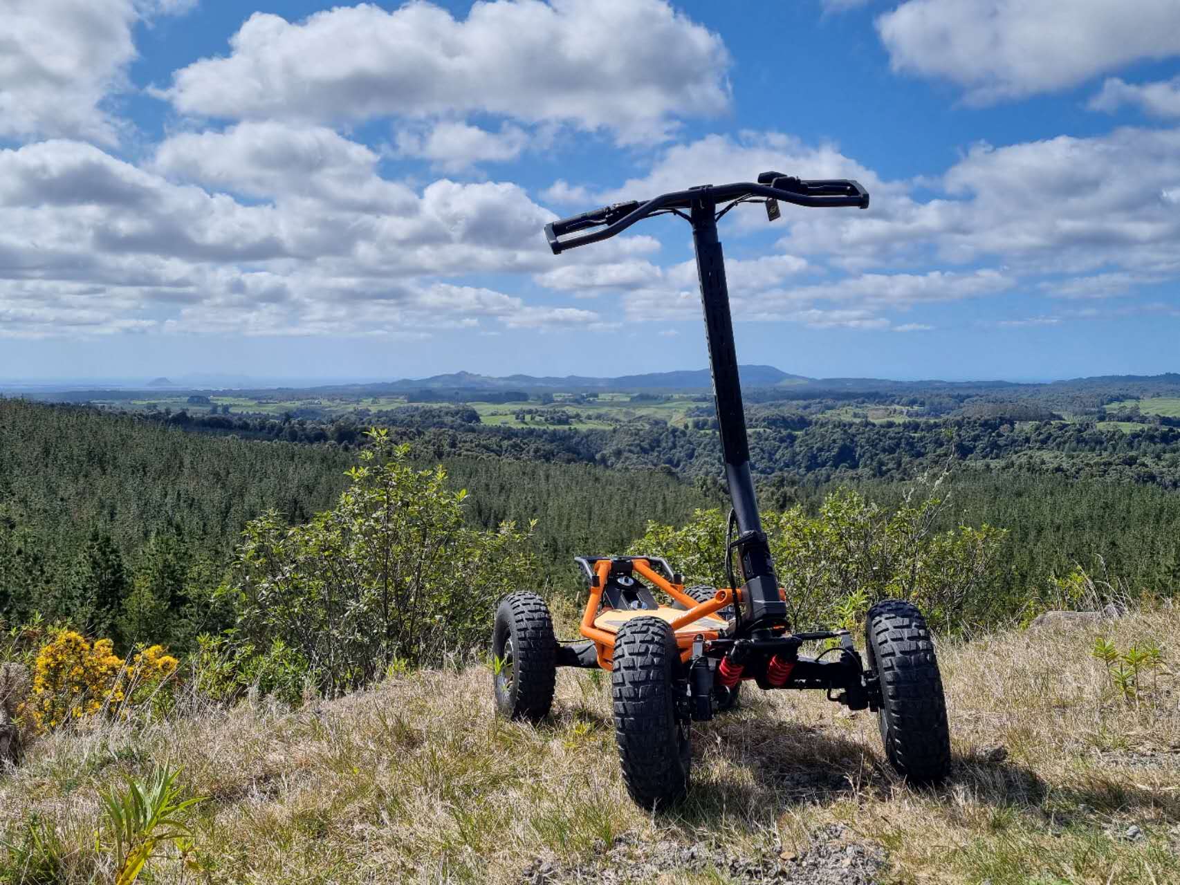 Veehop Electric ATV orange in grass on hill
