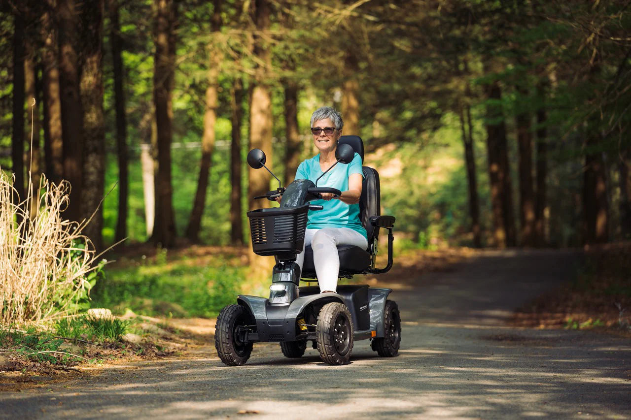 Person using a Pride Mobility Pathrider Endurance Mobility Scooter Black on a path in a forest