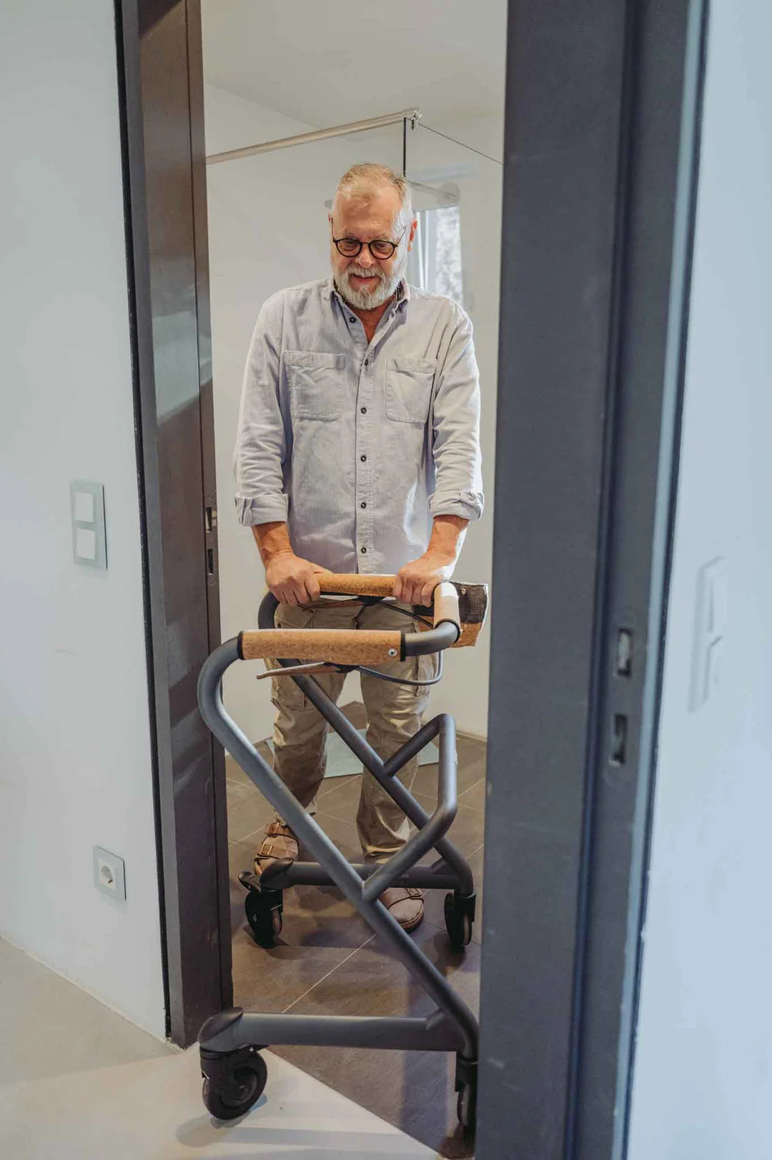 Man standing in front of a mirror with a Saljol Indoor Walker , wearing glasses and a light-colored shirt.