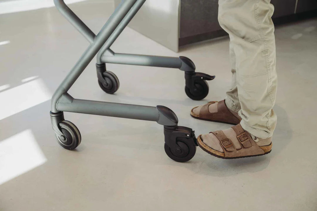 Person standing with Saljol Indoor Walker on a light-colored floor showing braked wheels