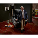 Man standing next to a Theorem Seagrove Power Lift Recliner Chair midnight in a stylish room with a dark wall and red floor.