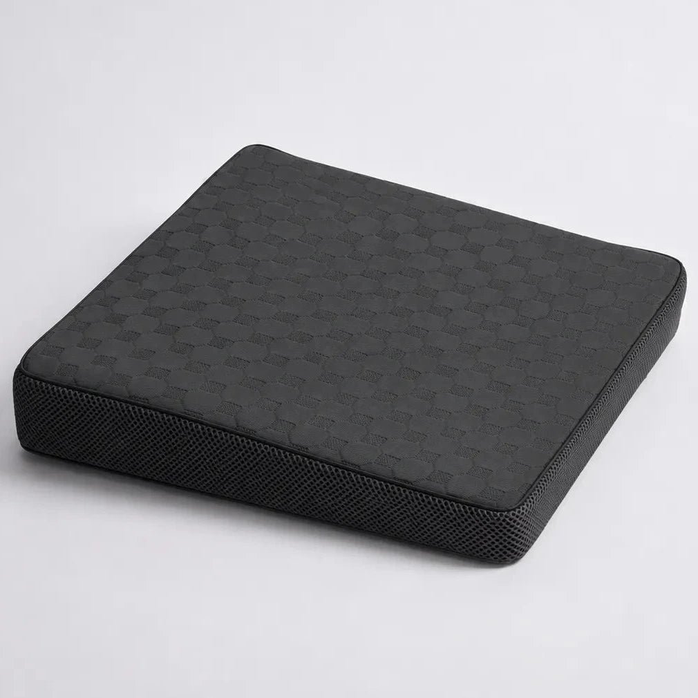 A charcoal icare Posture Wedge cushion with a textured honeycomb pattern on the top surface and a mesh-like side panel, shown on a light gray background.