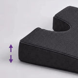 A close-up of a charcoal icare Coccyx Wedge with a purple double-arrow graphic indicating adjustable height, set against a plain light gray background.
