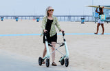 Woman with a  byACRE Nordic Pioneer walker on a beach with a pier in the background