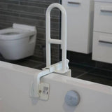 A white Roma Bath Grab Bar mounted to the side of a white bathtub in a modern bathroom setting with dark tiled floors and a toilet visible in the background.