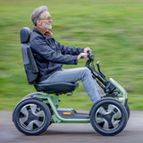 Man using a STERLING S800 by Scoozy All-Terrain Mobility Scooter on a blurred green outdoor background