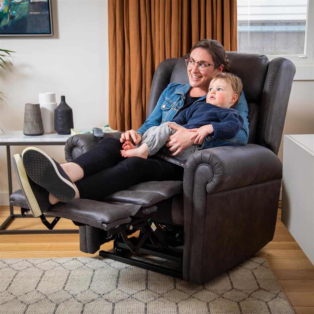 Woman and child sitting in a Theorem Aroki Power Lift Recliner Chair in a living room.